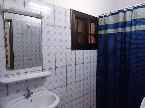ein Bad mit einem Waschbecken und einem Spiegel in der Unterkunft Résidence aux deux cocos in Lomé