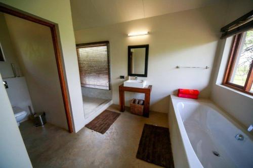 a bathroom with a tub and a toilet and a sink at Bushwillow Lodge, Royal Jozini PGR, eSwatini in Lavumisa