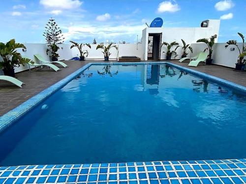 a large blue swimming pool with chairs and a building at Studio lumineux avec piscine/Gare casa oasis in Casablanca