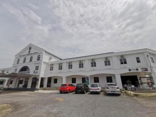 um grande edifício branco com carros estacionados num parque de estacionamento em THE ZULEY HERITAGE HOTEL em Kuala Perlis