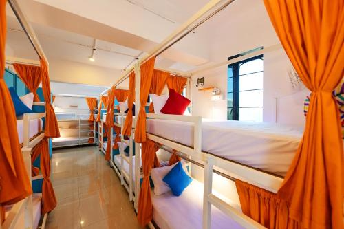 um quarto com 2 beliches e cortinas cor de laranja em goSTOPS Mumbai em Mumbai