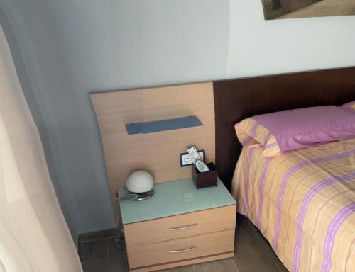 a bedroom with a bed and a nightstand with a alarm clock at Casa con Gran Piscina particular cerca playa in Torredembarra