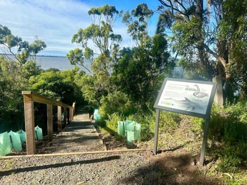a sign next to a trail with the ocean in the background at Bluelake Retreat in Metung