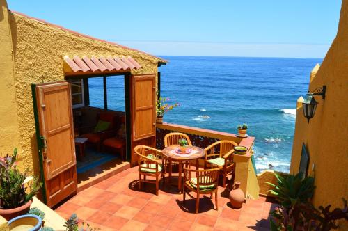 un patio con mesa, sillas y el océano en Casa Rural Virgen del Rosario en San Juan de la Rambla