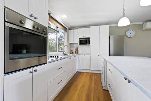 a kitchen with white cabinets and a large counter top at Bluelake Retreat in Metung