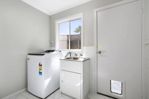 a white kitchen with a sink and a window at Bluelake Retreat in Metung