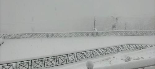 a wall covered in snow with a fence at Aaryam Resort, Auli in Joshīmath