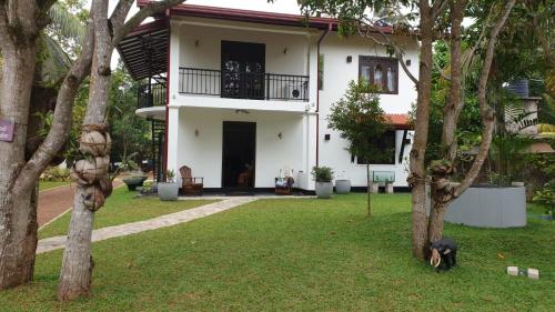 a white house with a dog standing in the yard at Chenu Villa Hikka in Hikkaduwa