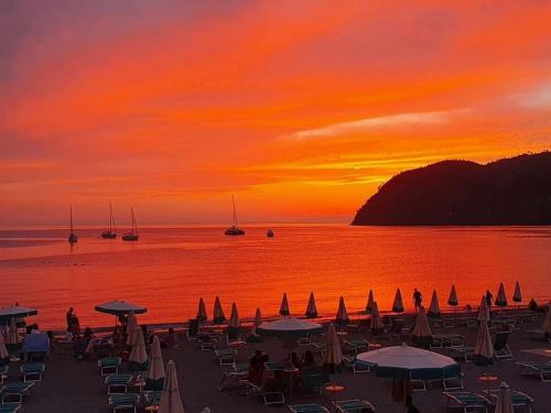 a sunset on a beach with umbrellas and boats at Beatrice Nel centro di Levanto in Levanto