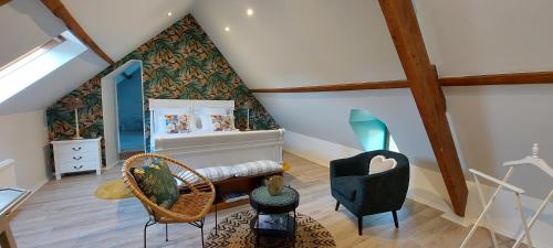 een zolderkamer met een bed en een stoel bij Manoir de Turqueville les Quatre Etoiles in Turqueville