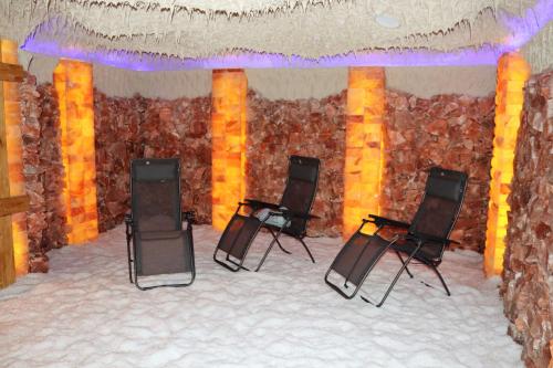 a room with three chairs and a stone wall at Appartement ROSalia in Forchtenstein