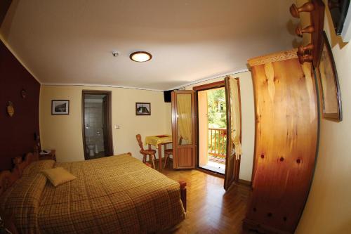 a bedroom with a bed and a door to a table at Green Hotel Herbetet in Cogne
