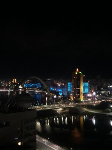 a view of a city at night with a bridge at Premium Apartments Esil Riverside in Astana
