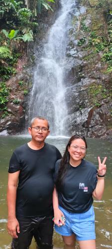 a man and woman standing in the water in front of a waterfall at DAOH'S Rooms & Scooters in Tanjung Rhu 