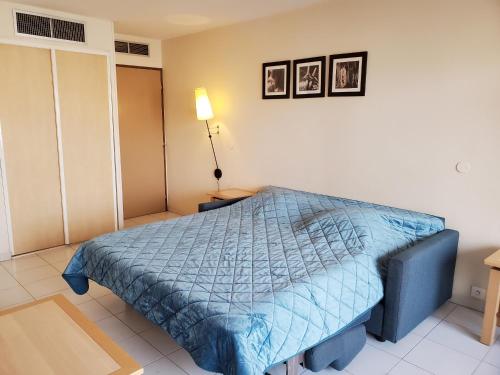 sypialnia z łóżkiem z niebieską kołdrą w obiekcie CAP HERMES Studio 31m2 Vue Port Climatise piscine, w Fréjus