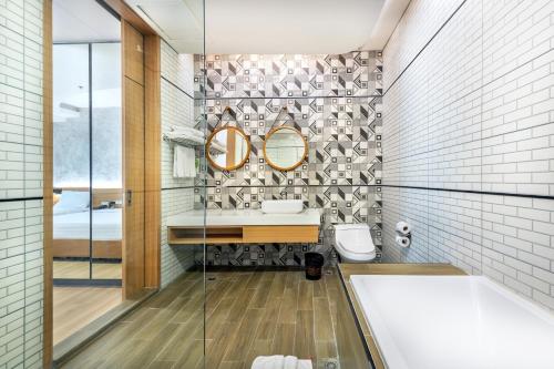 a bathroom with a tub and a sink and mirror at Qiu Hotel Sukhumvit SHA Plus in Bangkok
