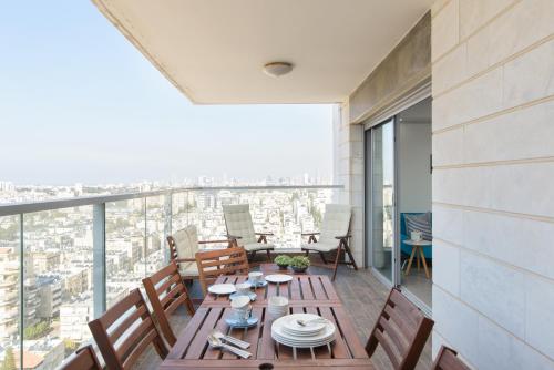 a dining room with a table and chairs on a balcony at Deluxe & Terrace with City Overview by FeelHome in H̱olon