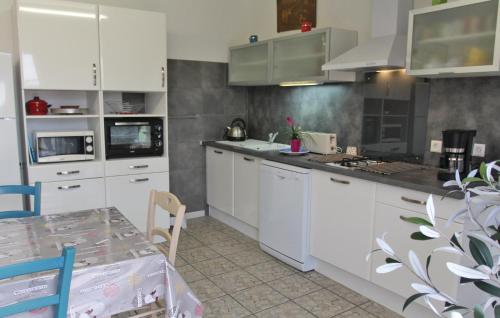 une cuisine avec des armoires blanches et une table à l'intérieur dans l'établissement Lovely Home In Rochefort Du Gard, à Rochefort-du-Gard