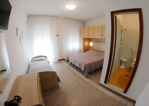 Habitación pequeña con cama y espejo. en Albergo Rosa, en Cavallino-Treporti