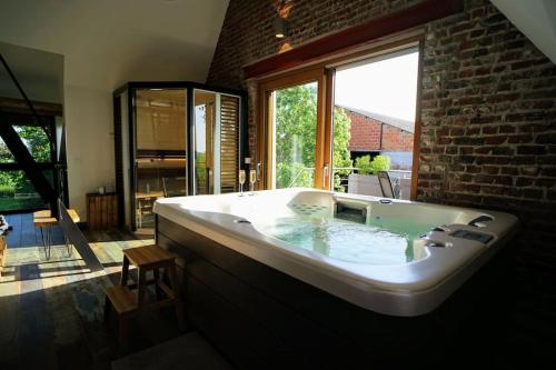 a large bath tub in a room with a window at Spa privatif à la ferme - Haut de gamme - Atypique in Bois-Grenier