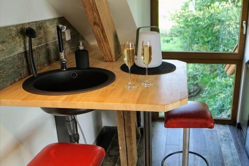 a kitchen with a sink and two glasses of wine at Spa privatif à la ferme - Haut de gamme - Atypique in Bois-Grenier