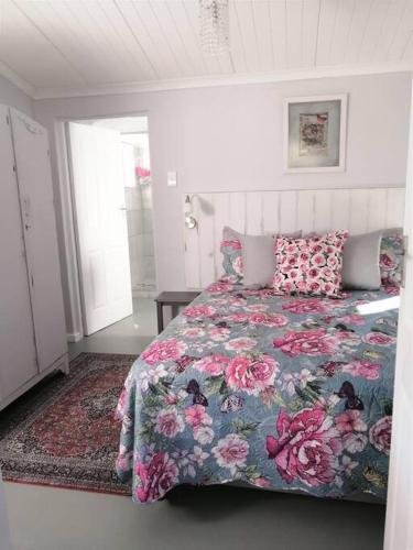a bedroom with a bed with a floral bedspread at Rose Cottage AtTheDairyShed in Heidelberg