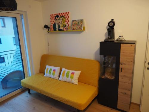 a yellow couch with two pillows in a living room at Ahorn 4 in Gröbming