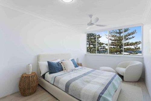 a white bedroom with a bed and a window at Beachfront Luna Apartment in Gold Coast