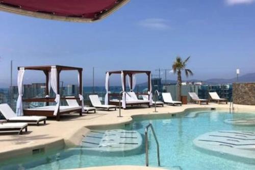 - une piscine avec des chaises longues blanches dans un bâtiment dans l'établissement 5 star Luxurious Ocean Spa Plaza, à Gibraltar