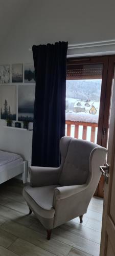 a reclining chair in a room with a window at Apartamenty Homole Mansarda in Szczawnica