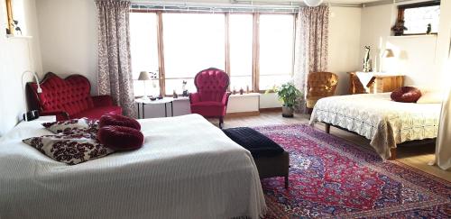 a bedroom with two beds and two red chairs at Villa Vy in Rättvik