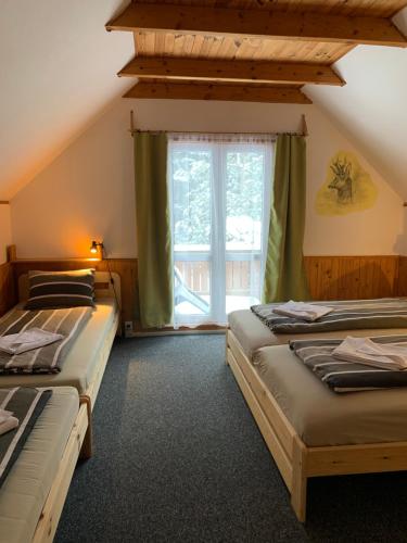 2 camas en una habitación con ventana en Chata Jezevec, en Hojsova Stráž