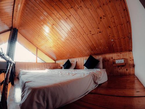 a bed in a room with a wooden ceiling at Roamate Hostel, Old Manali in Manāli