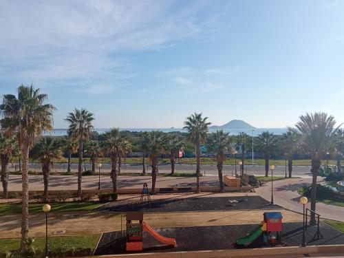 un parque con palmeras y un parque infantil en COMFORT SUITE La Manga, marina & beach, en La Manga del Mar Menor