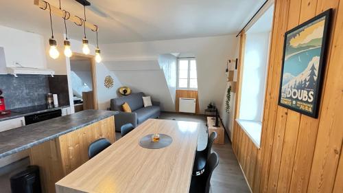 Le Coeur de Pontarlier في بونتارليه: مطبخ وغرفة معيشة مع طاولة خشبية