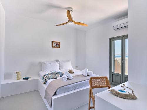 a white bedroom with a bed and a ceiling fan at Siora of Paros - Ammiralis & Castelis in Naousa