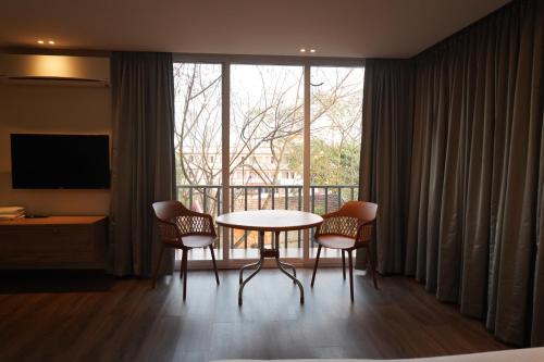 Zimmer mit einem Tisch und Stühlen sowie einem großen Fenster in der Unterkunft Hotel Bekal International in Kasaragod