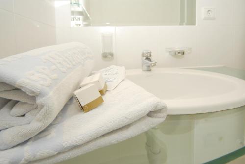 a bathroom with white towels and a sink at Hotel Rose Wenzer in Vols am Schlern