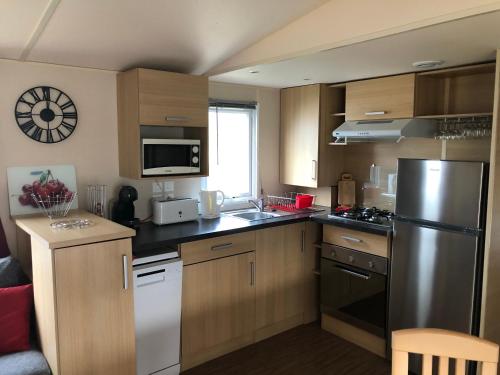 a kitchen with wooden cabinets and a stainless steel refrigerator at Grand mobil home exposé sud, 2 salles de bain in Onzain