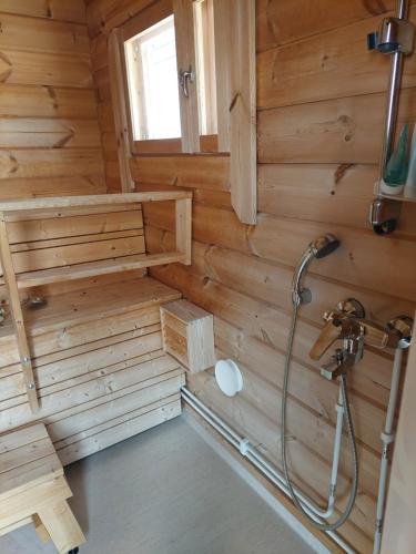 a bathroom with a shower in a wooden wall at Apteekkarinmökki in Forssa