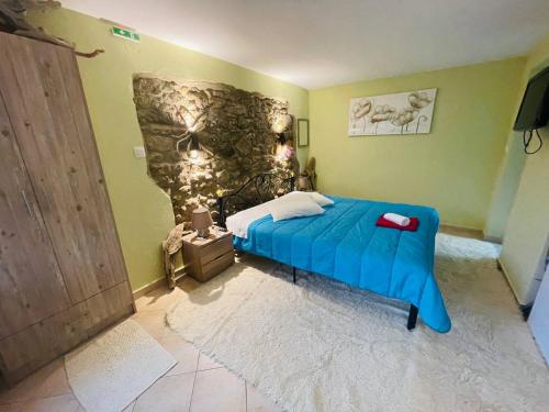 a bedroom with a blue bed and a stone wall at Fergani Apartments in Moudhros