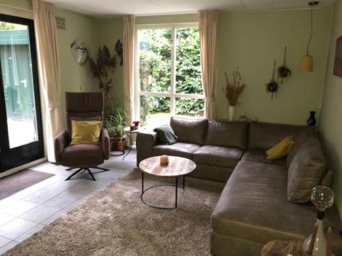 a living room with a couch and a table at De Zingende Wilg, heerlijk huisje met Hottub in Ewijk