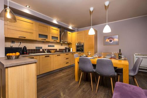 a kitchen with wooden cabinets and a table and chairs at Dufti Home in Plovdiv Center & Old Town / Kapana in Plovdiv