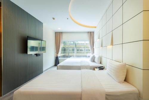 a hotel room with two beds and a tv at Qiu Hotel Sukhumvit SHA Plus in Bangkok