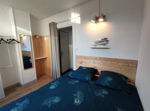 Schlafzimmer mit einem Bett mit blauer Bettwäsche in der Unterkunft Douceurs du littoral in Calais