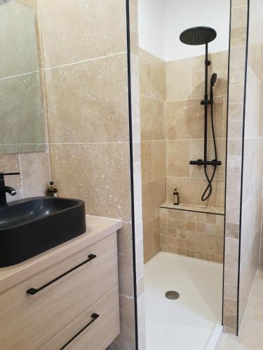 La salle de bains est pourvue d'une douche, d'un lavabo noir et d'une baignoire. dans l'établissement Stella Marina, à Macinaggio