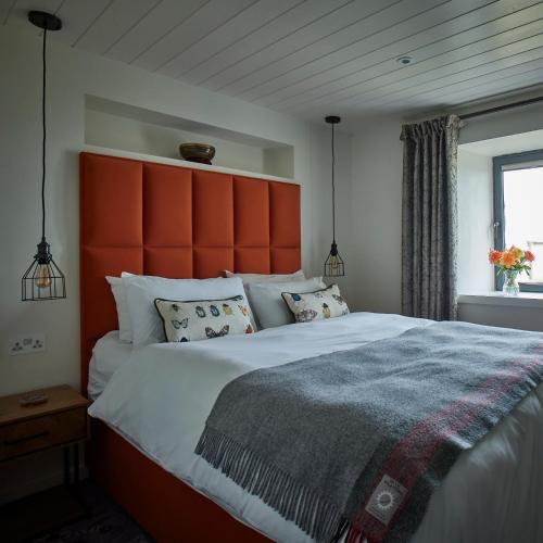 a bedroom with a large bed with an orange headboard at Monkstadt No 10 The Horse Walk in Totscore