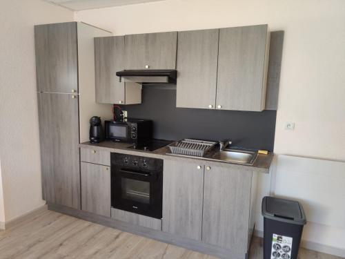 a kitchen with a sink and a stove and cabinets at Appartement rénové tout confort, centre Valdahon in Le Valdahon