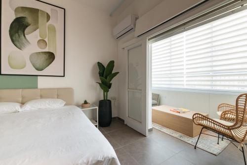 ein Schlafzimmer mit einem Bett, einem Stuhl und einem Fenster in der Unterkunft O&O Group - Stunning Chic 2 BR Ibn Gvirol St in Tel Aviv