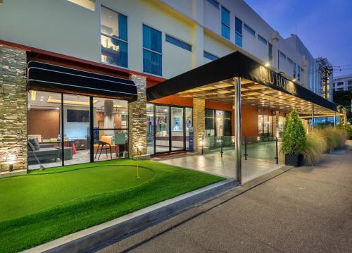 un bâtiment avec une pelouse verte devant lui dans l'établissement Qiu Hotel Sukhumvit SHA Plus, à Bangkok